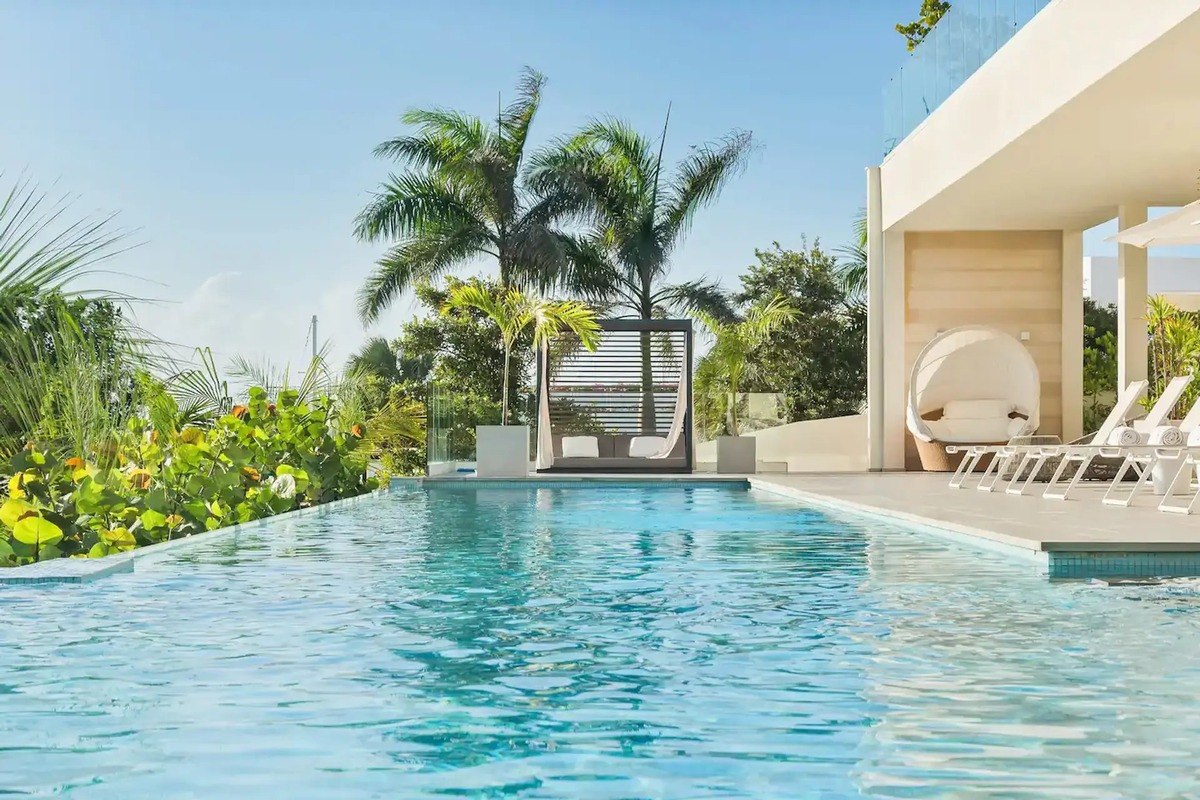 Infinity pool has lounge chairs and tropical landscaping.