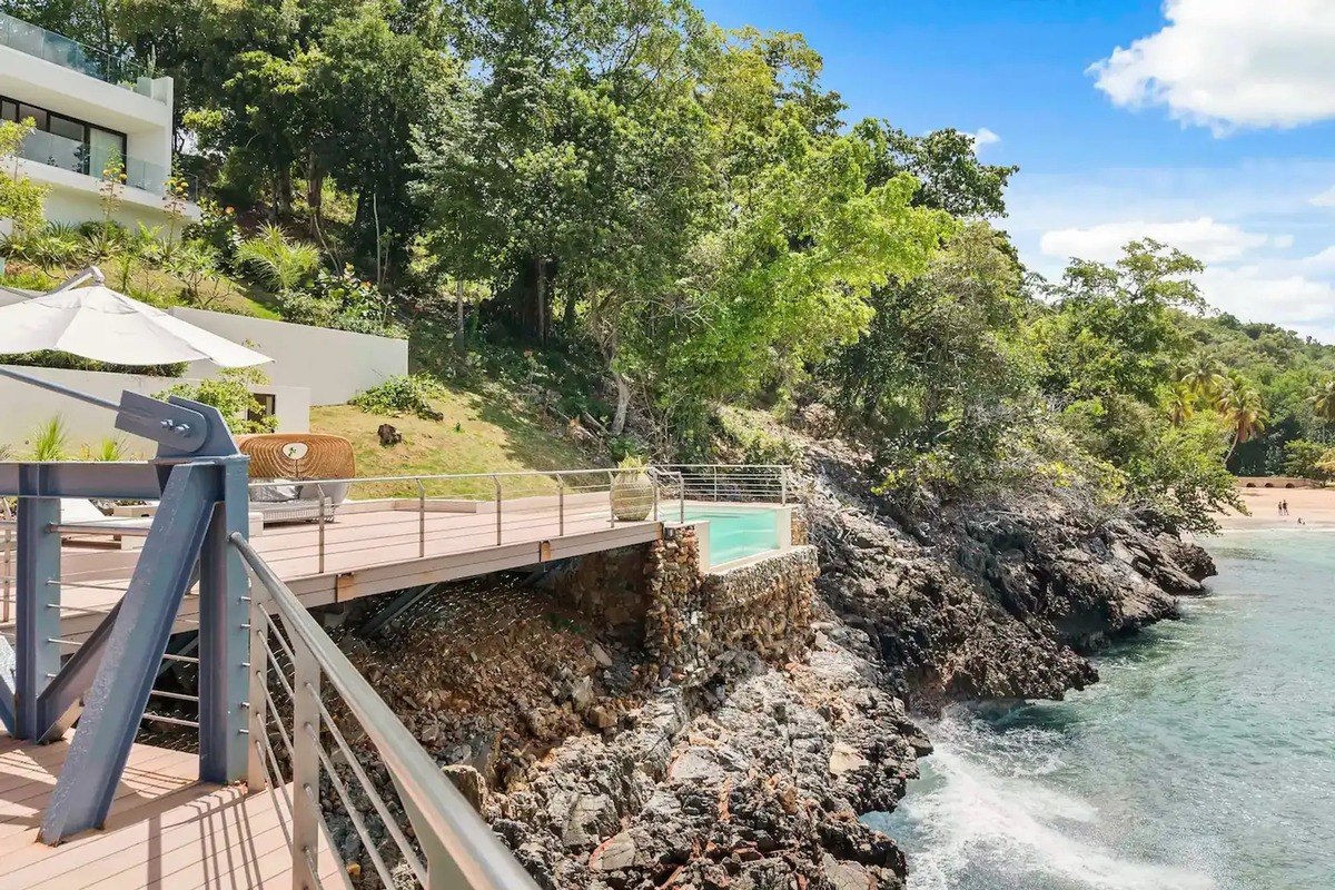 Oceanfront deck has infinity pool and walkway leading to beach.