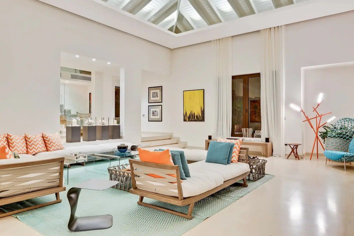 Living room has light wood daybeds, high ceilings, and light colored walls.