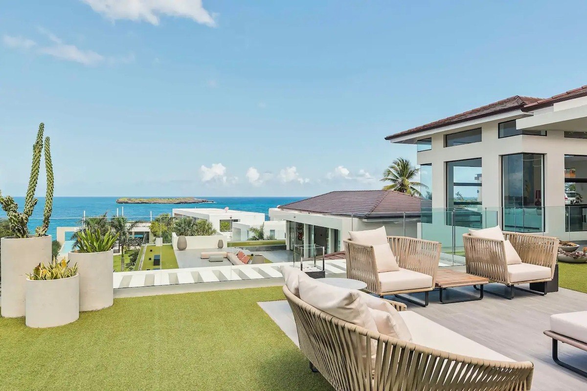 Rooftop patio has wicker furniture, artificial turf, and ocean view.