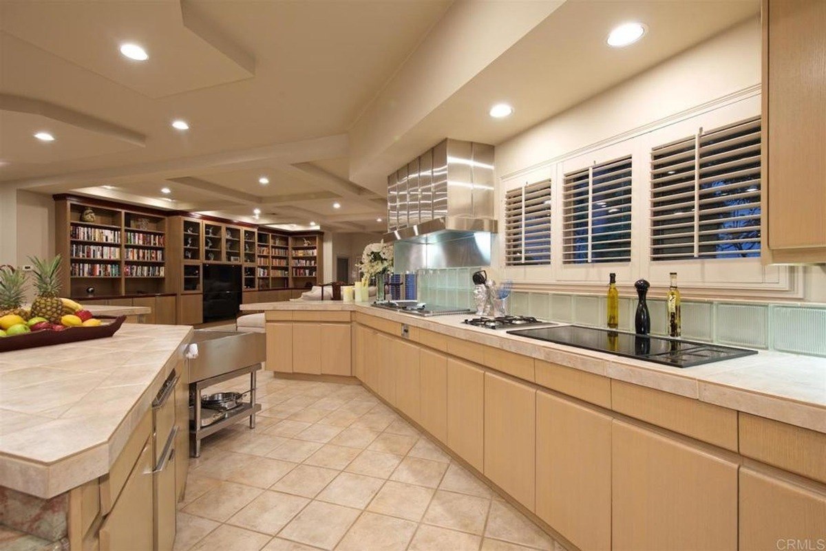 Spacious kitchen with light cabinetry, tiled flooring, and ample counter space illuminated by recessed lighting.