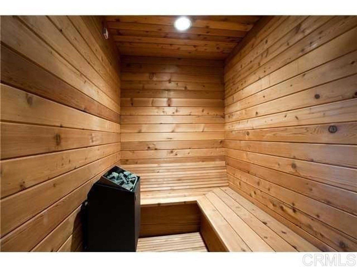 Cedar-paneled sauna featuring a black electric heating unit and built-in wooden bench seating.