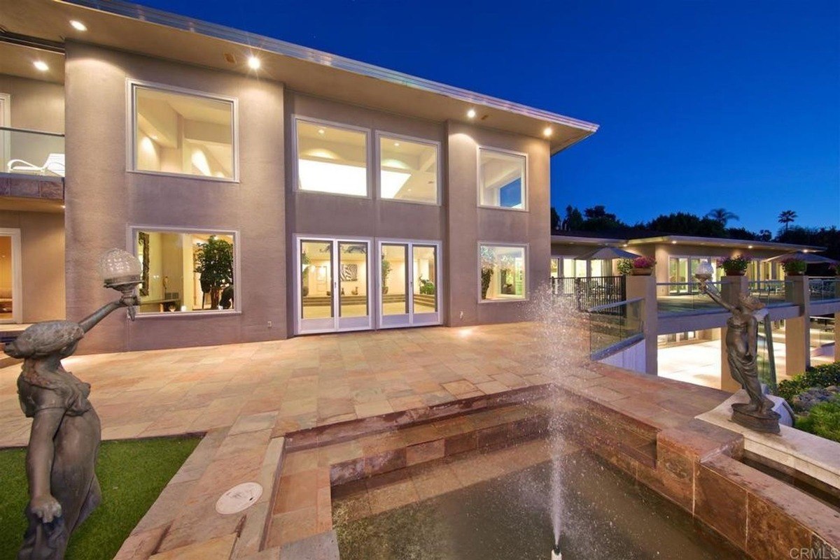 Outdoor patio with water fountain features and expansive windows displaying soft evening lighting.