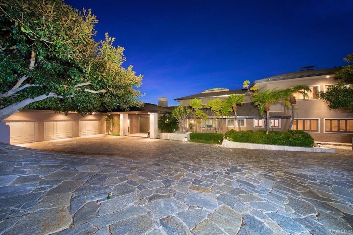 Driveway area showcases a broad entrance lined with greenery and illuminated under a deep blue sky.