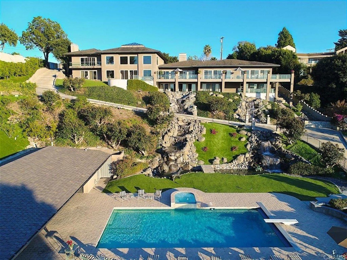 View of the hillside estate highlights waterfalls, greenery, and a pool with stone surroundings.