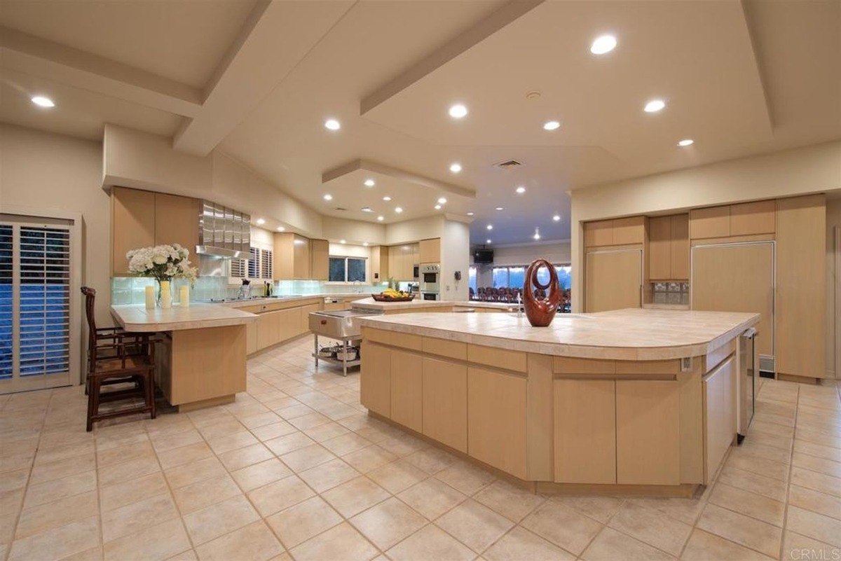 Expansive kitchen layout featuring light wood cabinetry, an oversized island, and recessed lighting.