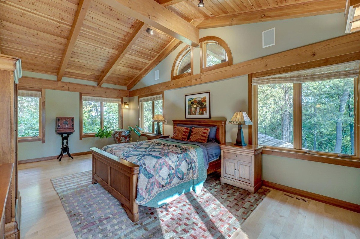 Spacious bedroom with a vaulted ceiling, large windows, and a warm wood aesthetic offers a tranquil retreat with plenty of natural light.