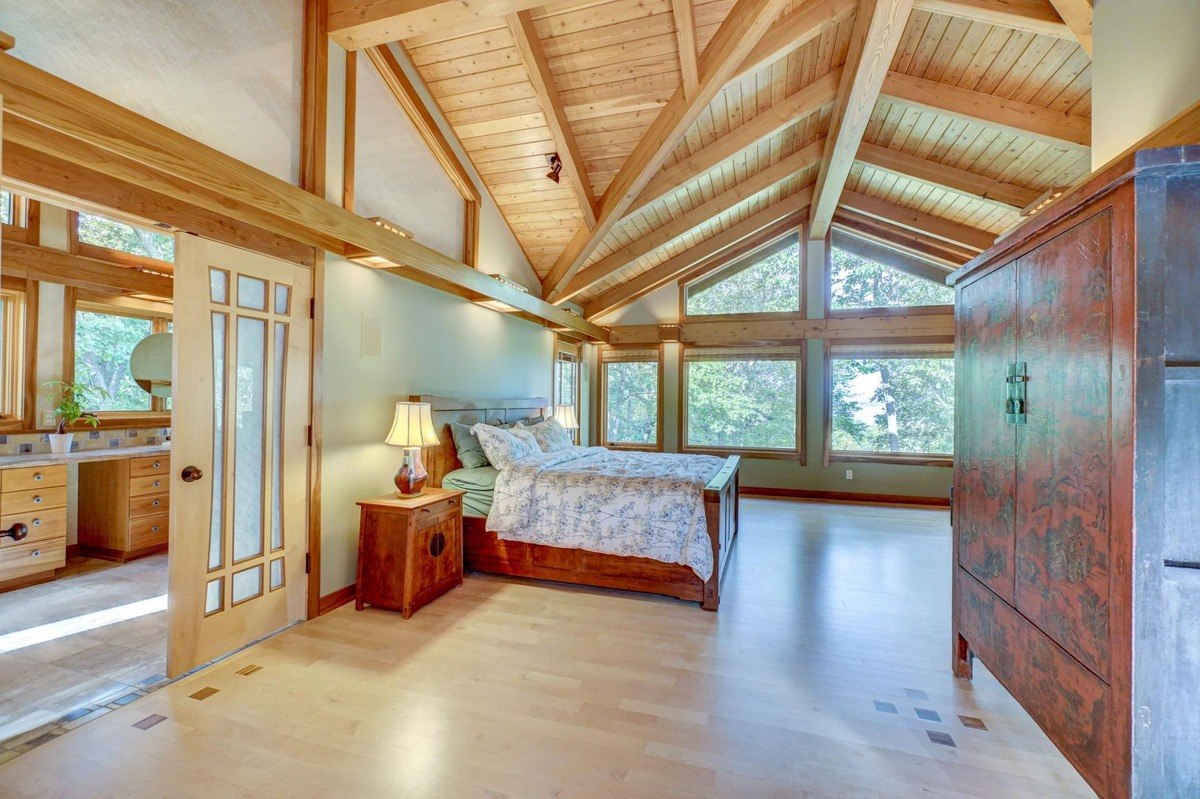 Vaulted ceiling create a cozy and inviting atmosphere in this spacious bedroom, featuring a comfortable bed and ample natural light.