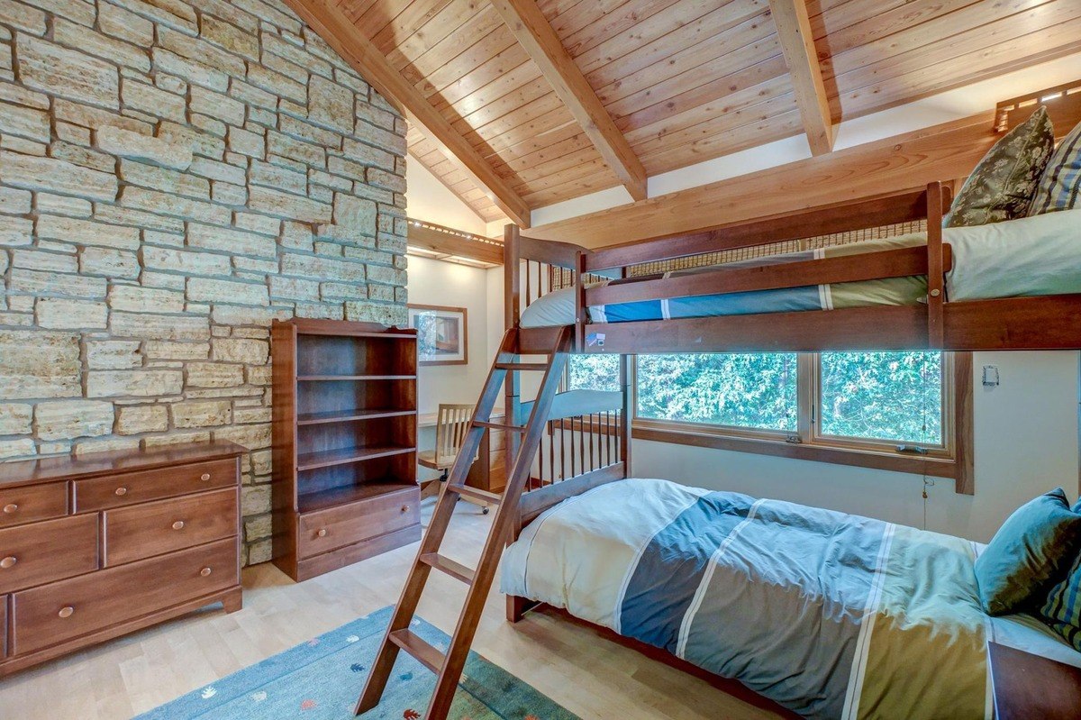 Cozy bedroom with a stone accent wall, a set of bunk beds, and a warm wood aesthetic offers a comfortable space for children.