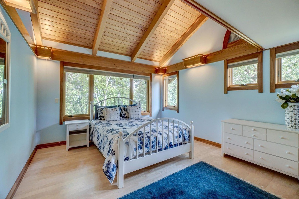 Bedroom with a vaulted ceiling, large windows, and a warm wood aesthetic offers a relaxing retreat with plenty of natural light.