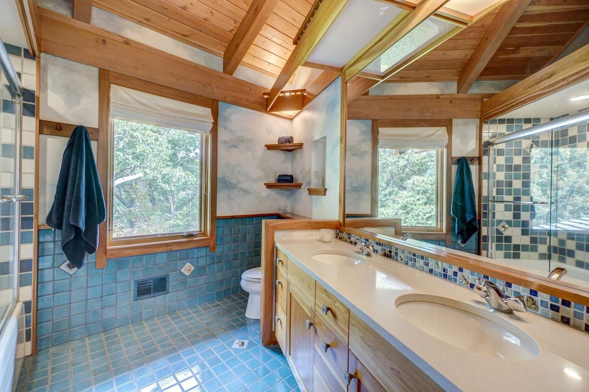 Bright and airy bathroom with blue tile accents, a double vanity, and a sky mural creates a spa-like atmosphere.