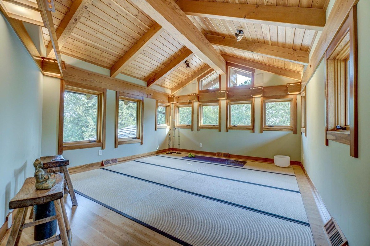 Vaulted ceiling and large windows creates a serene setting for yoga or meditation, featuring tatami mats and a peaceful atmosphere.