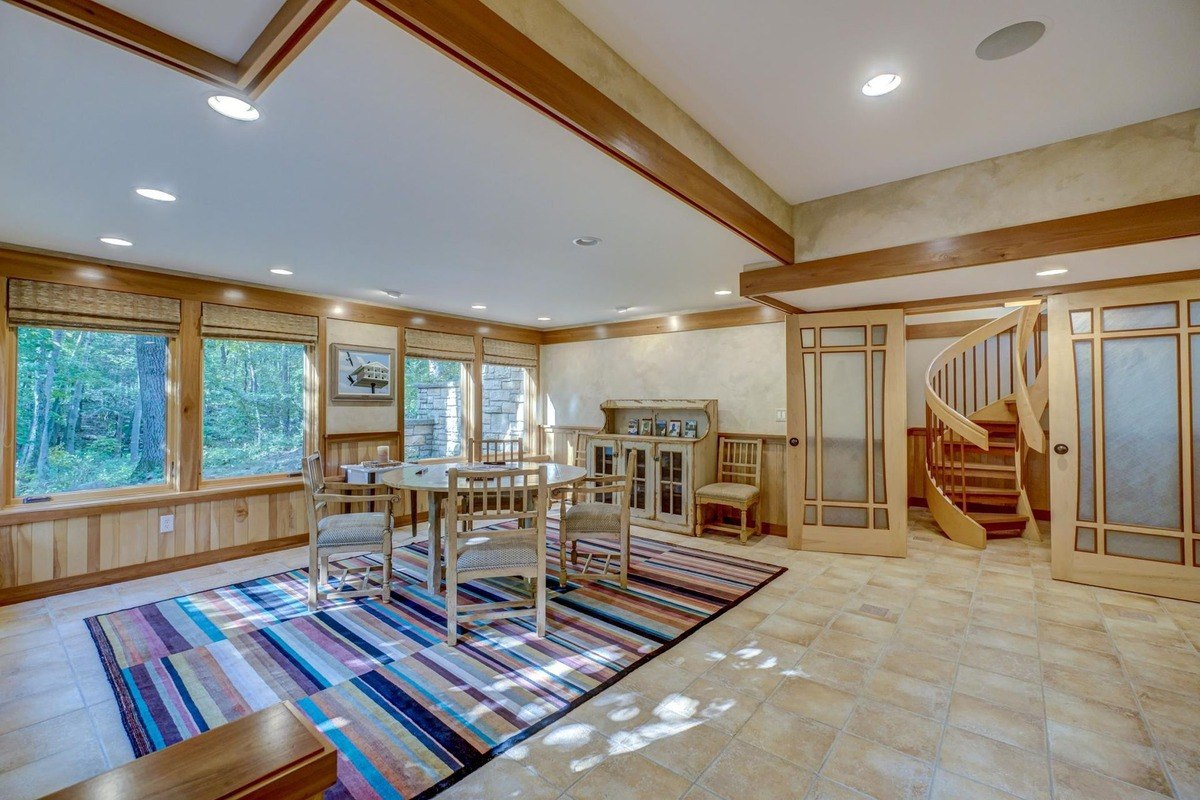 Inviting room features a colorful rug, a dining table, and a spiral staircase, creating a unique and stylish space.