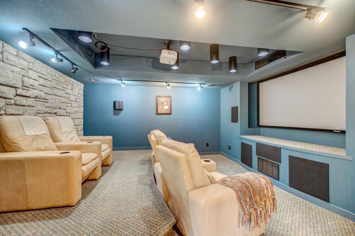 Dark walls and a projector screen create a cinematic atmosphere in this dedicated home theater, featuring comfortable seating and state-of-the-art technology.