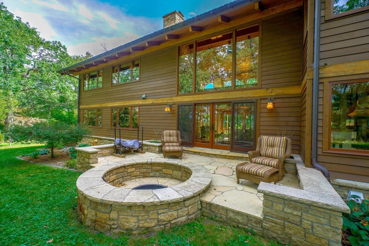 Charming home with a stone patio and fire pit offers a welcoming outdoor space surrounded by lush greenery.