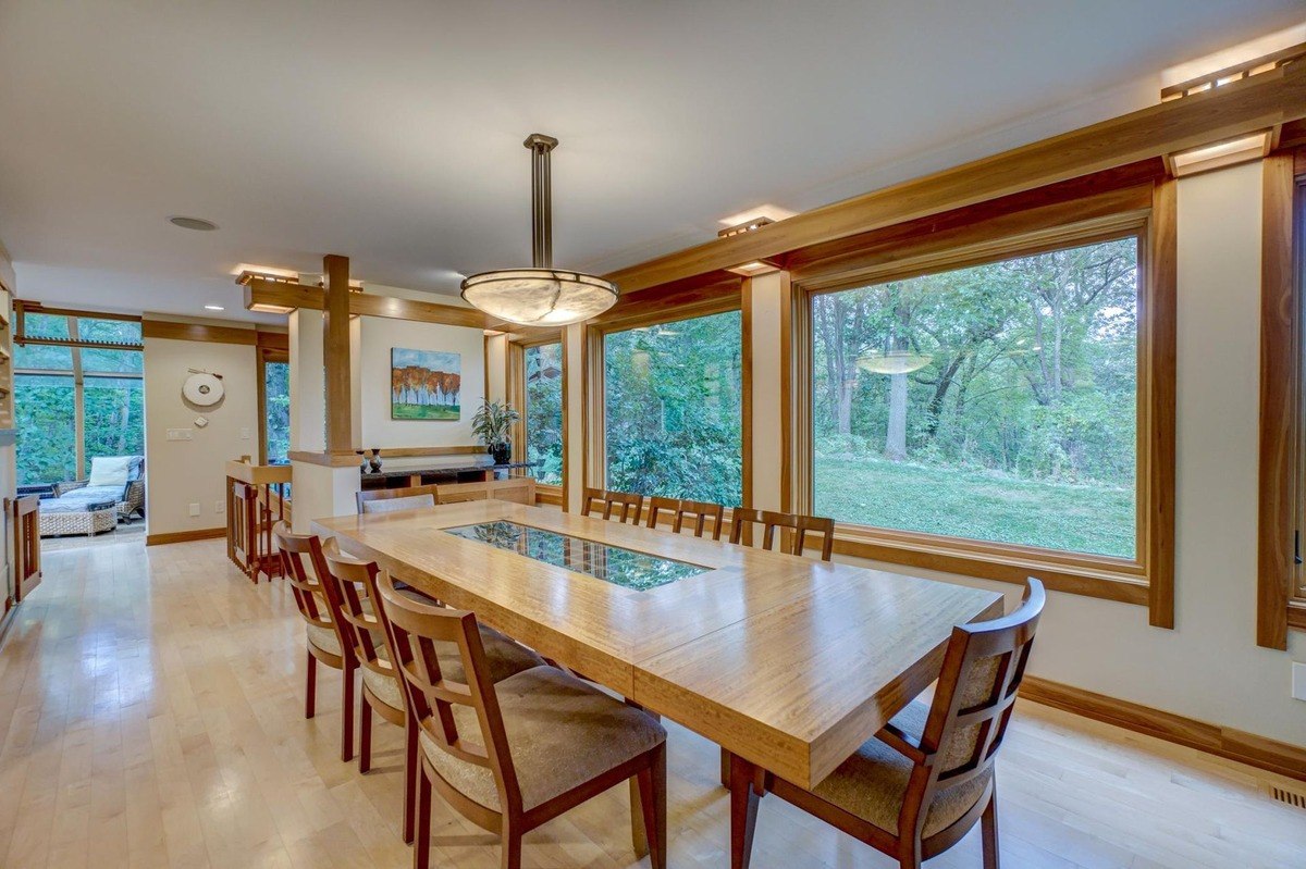 Natural light fills this elegant dining room, which features a large table, comfortable chairs, and a modern chandelier.