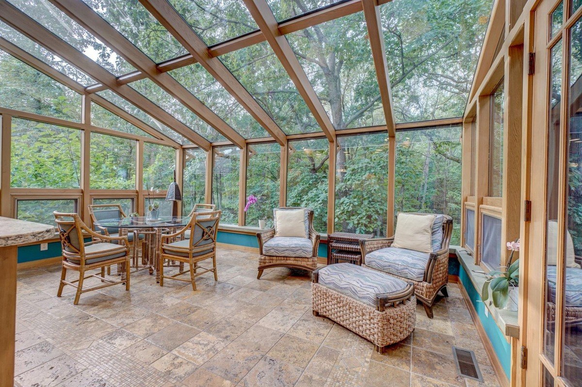 Sun-drenched solarium with a vaulted ceiling and floor-to-ceiling windows offers a relaxing retreat with comfortable seating and a dining area.