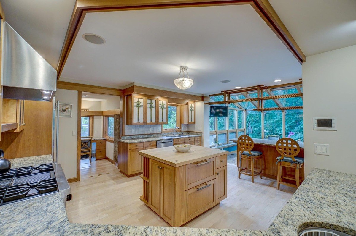 Natural light fills this open-concept kitchen, featuring a central island, ample counter space, and a view of the surrounding natural landscape.