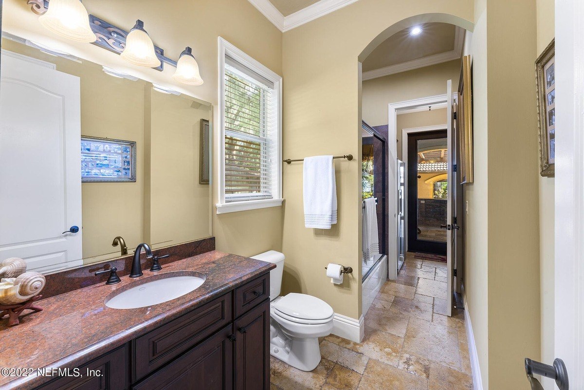 Bathroom has granite countertop, dark wood cabinets, and a toilet.