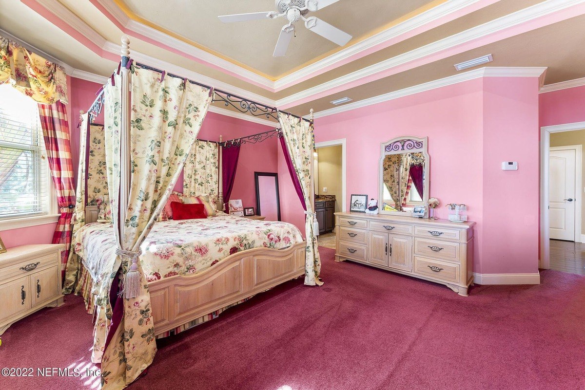 Bedroom has pink walls, a floral-print canopy bed, and a light wood dresser.