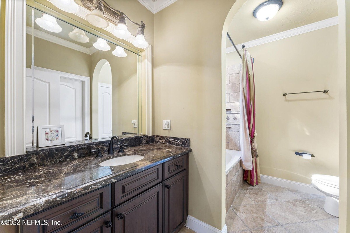 Bathroom has dark wood vanity with granite countertop, and a shower/tub combo.