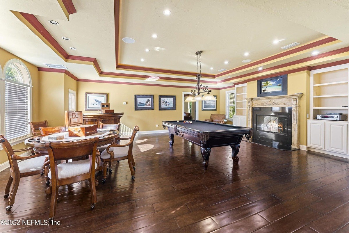 Game room features a pool table, wood floors, and built-in shelving.