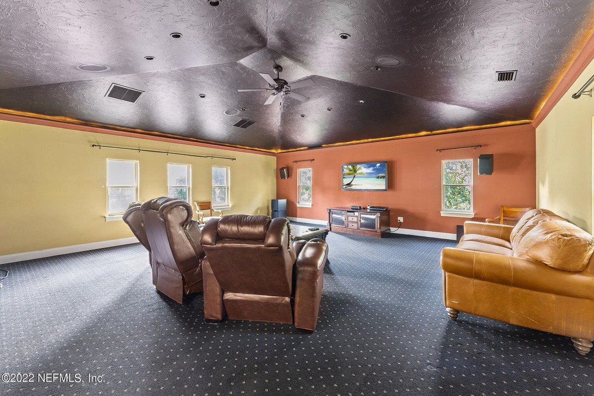 Media room has brown leather recliners, a flat-screen TV, and a dark ceiling.