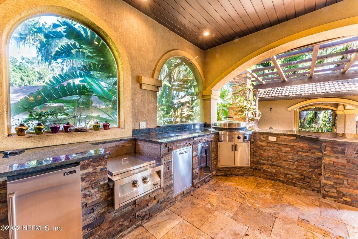 Outdoor kitchen features granite countertops, stainless steel appliances, and stone veneer.