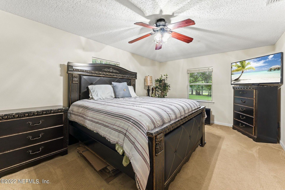 Bedroom has a dark wood bed frame, striped bedding, and a flat-screen TV on a dresser.