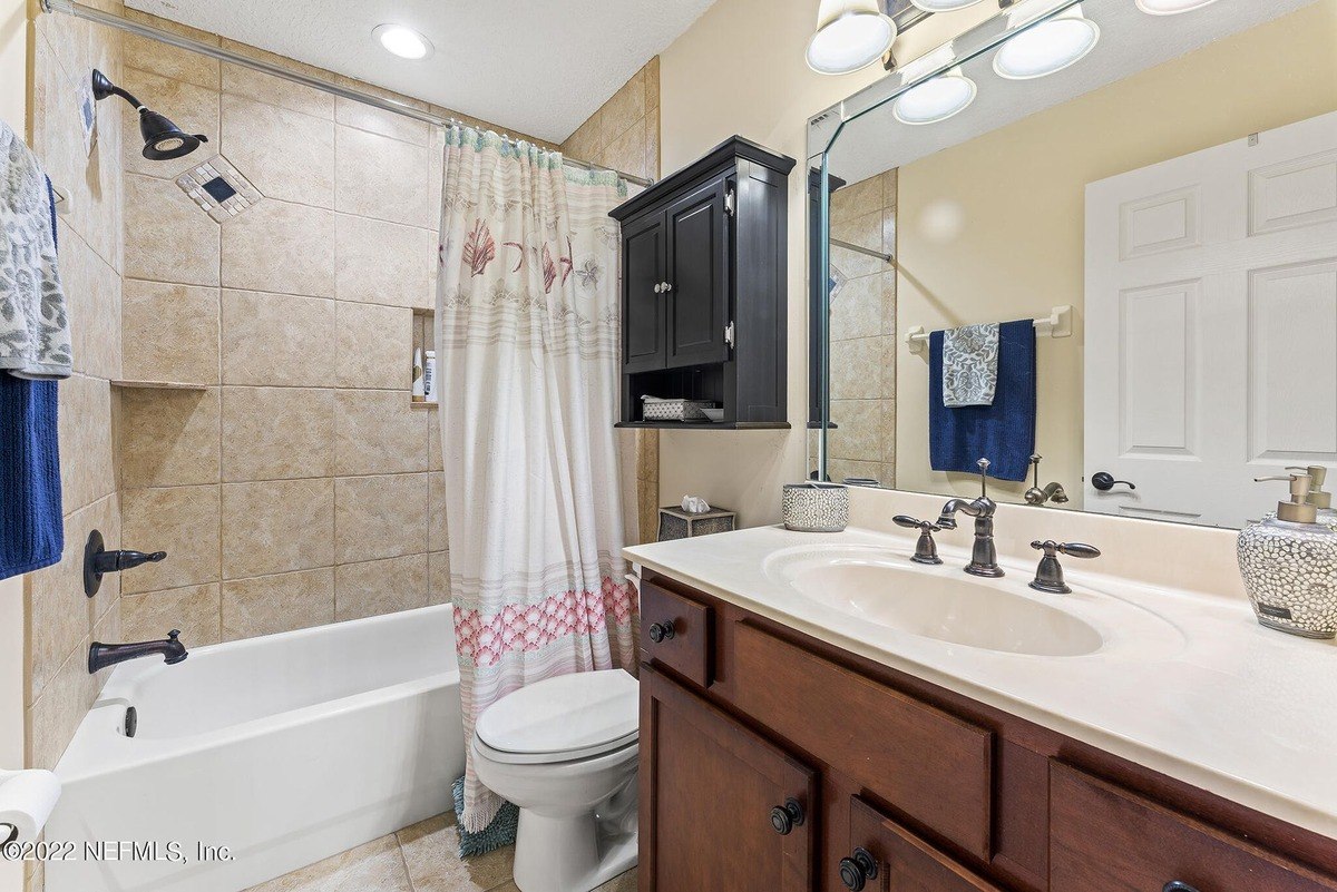 Bathroom has a tub, shower, and dark wood vanity with a light countertop.