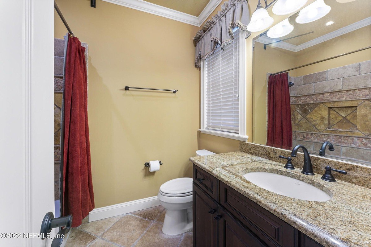 Bathroom has granite countertop, dark wood cabinets, and a shower/tub combo.