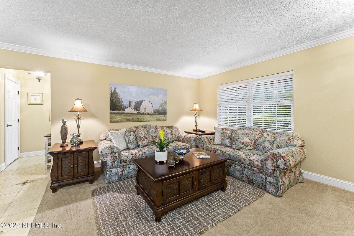 Living room has floral couches, coffee table, and a painting of a barn.