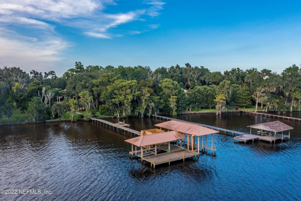 Waterfront property has multiple docks and a large house nestled among trees.