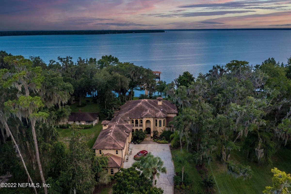 Large home sits on waterfront property with a beautiful sunset view.