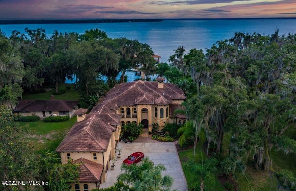 Large home is situated on waterfront property with a beautiful sunset.