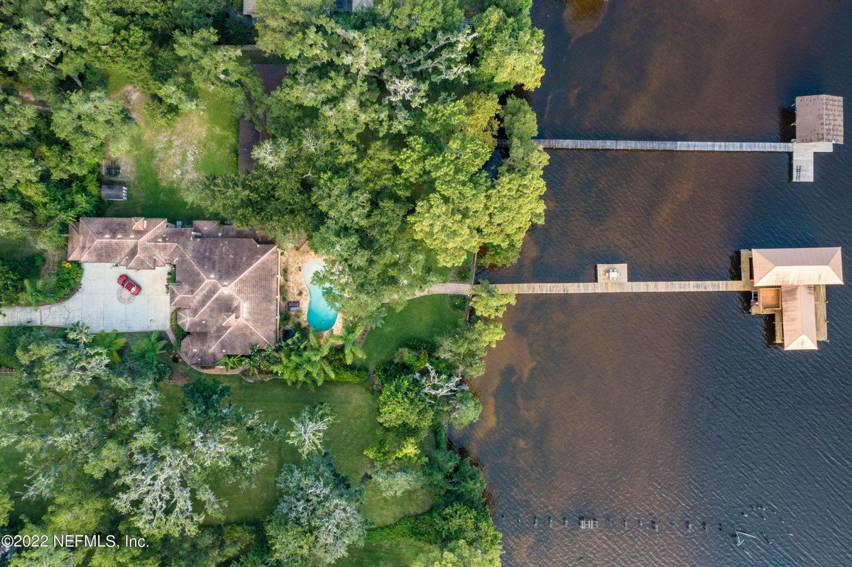 Aerial view shows waterfront home with pool and multiple docks.