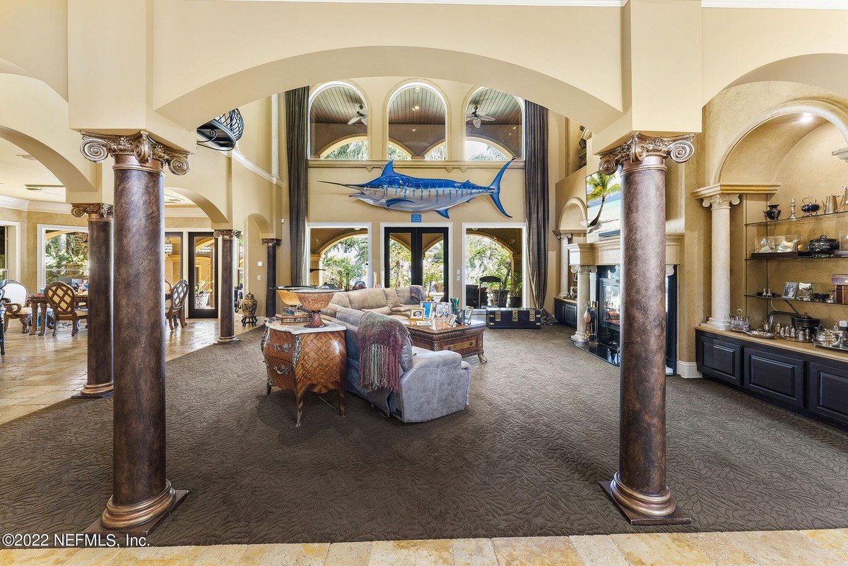 Large living room has high ceilings, columns, and a large fish mounted on the wall.