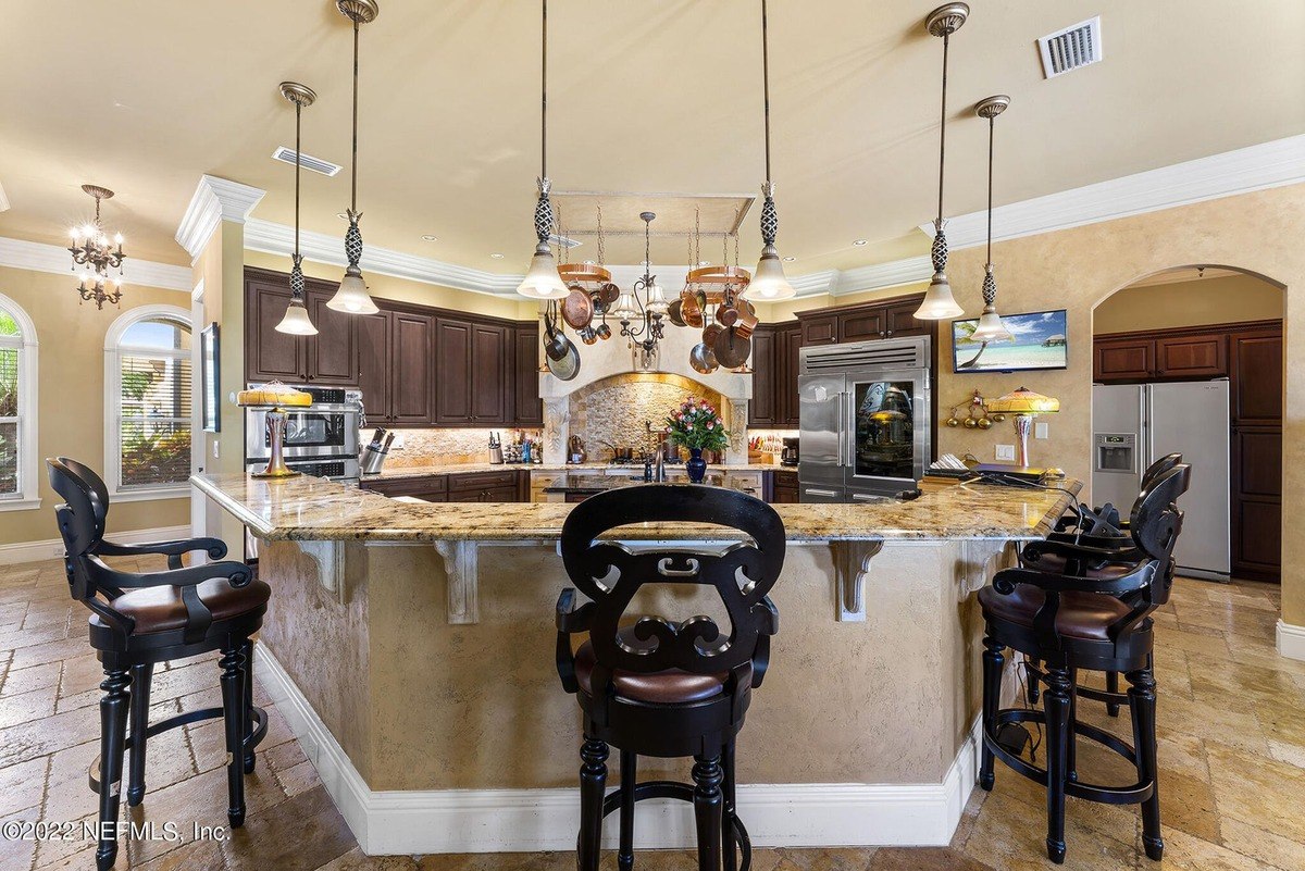 Large kitchen features granite countertops, dark wood cabinets, and pendant lighting.