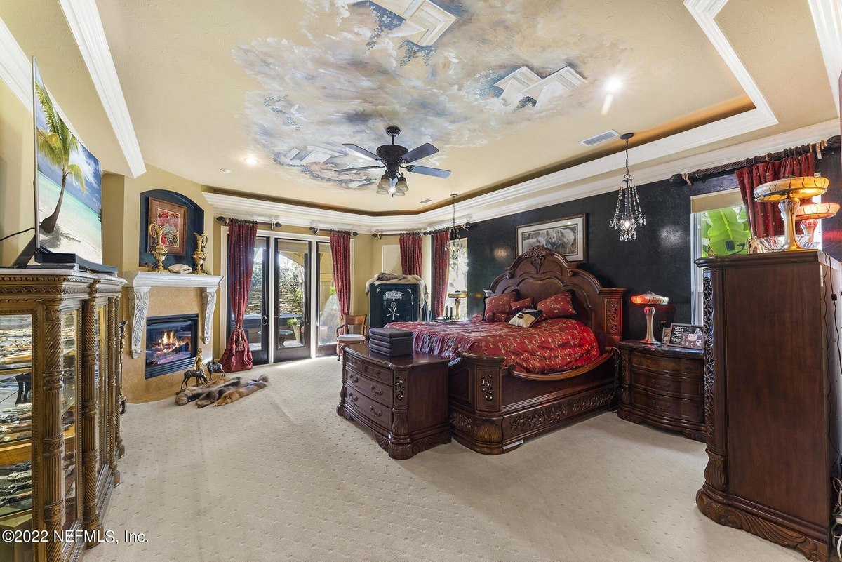 Master bedroom features a large bed, painted ceiling, and dark wood furniture.