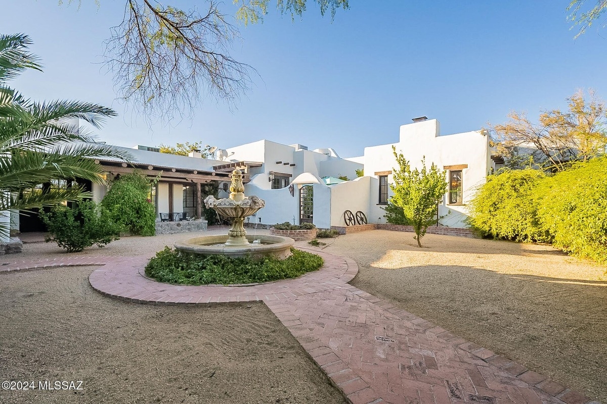 Circular fountain with brick pathways surrounded by desert landscaping in the courtyard.