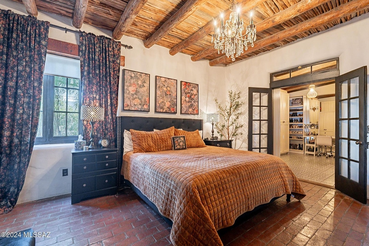 Bedroom showcases a rustic ceiling with wooden beams, floral decor, and warm lighting.