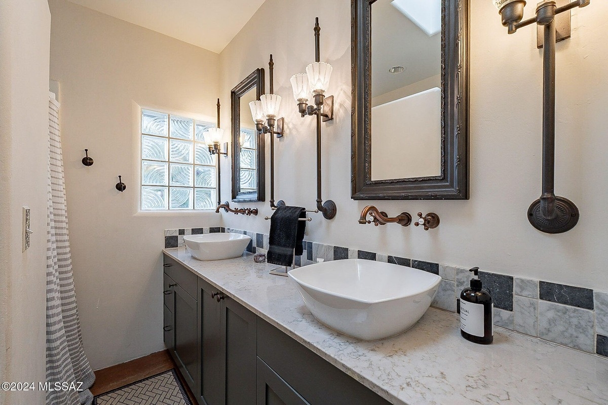 Bathroom with double sinks, dark gray cabinets, and unique lighting fixtures.