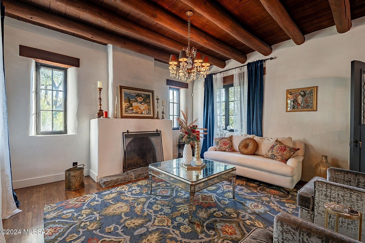 Cozy living room with a rustic fireplace, exposed wood beams, and decorative accents.