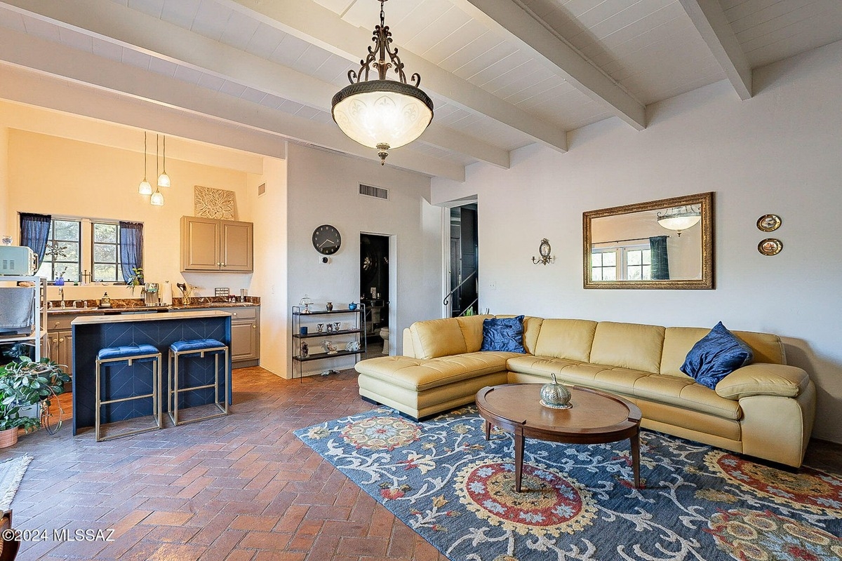 Open floor plan living room with a kitchen, yellow sectional sofa, and a large area rug.