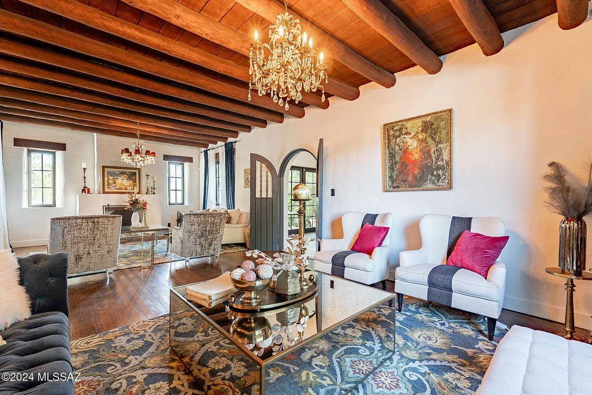 Spacious living area with chandeliers, arched doorways, and stylish seating.