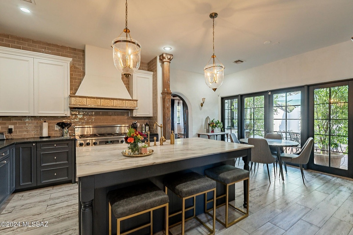 Dining area adjacent to the kitchen with large windows overlooking outdoor greenery.