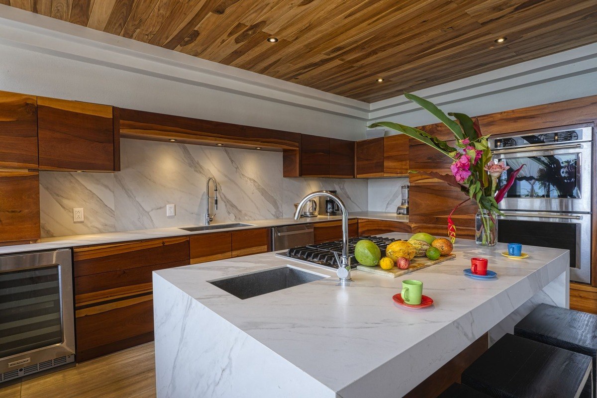 Kitchen has wood cabinets, marble countertops, and wood ceiling.