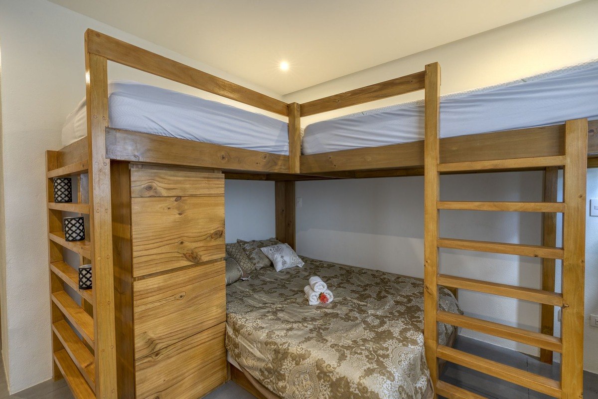 Room has wooden bunk bed with shelves and drawers.