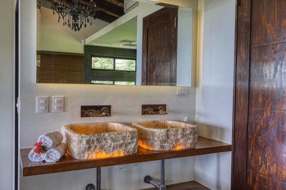 Bathroom has double sinks made of stone and wood vanity.