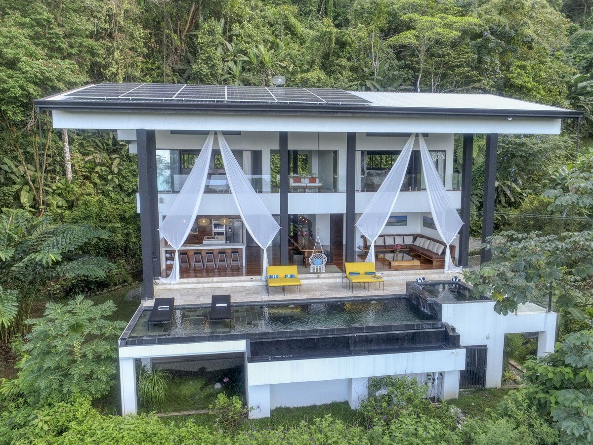 Modern house has infinity pool and solar panels on roof.